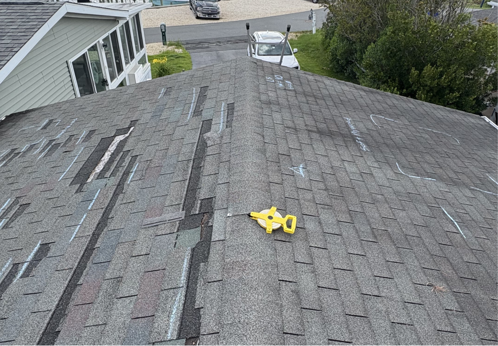 Roof ridge with missing shingle tabs and inspection chalk markings